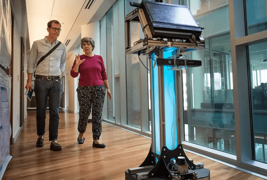 Two CMU faculty members following an autonomous robot down a hallway.